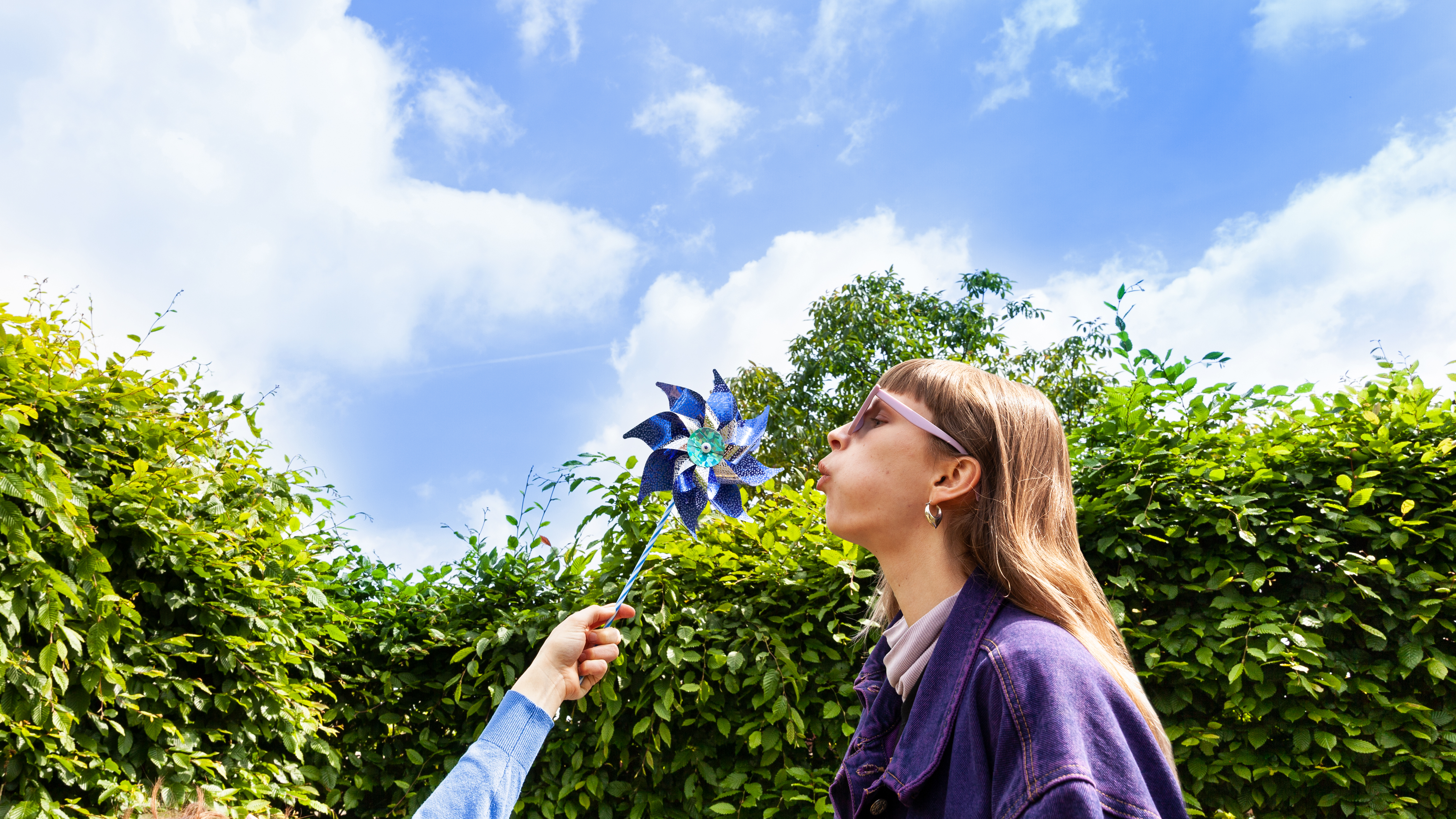 Vrouw blaast tegen een papieren windmolentje. Ze is opgewekt, net als de windstroom van Greenchoice.