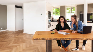 Twee vrouwen met een laptop en een contract op tafel